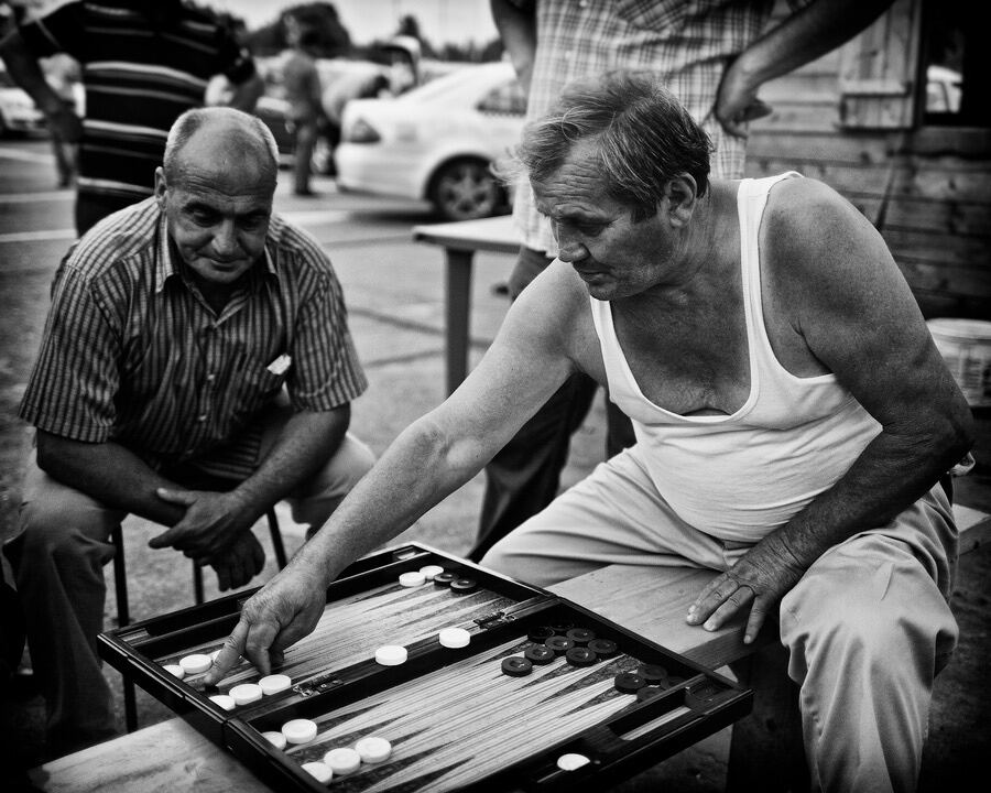 Zwei Männer spielen Backgammon an einem Tisch im Freien
